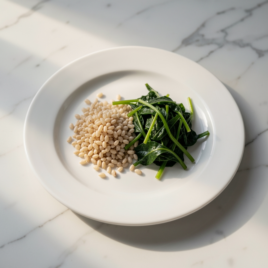 A simple white ceramic plate with a measured portion of grains and greens on a clean marble surface in soft morning daylight